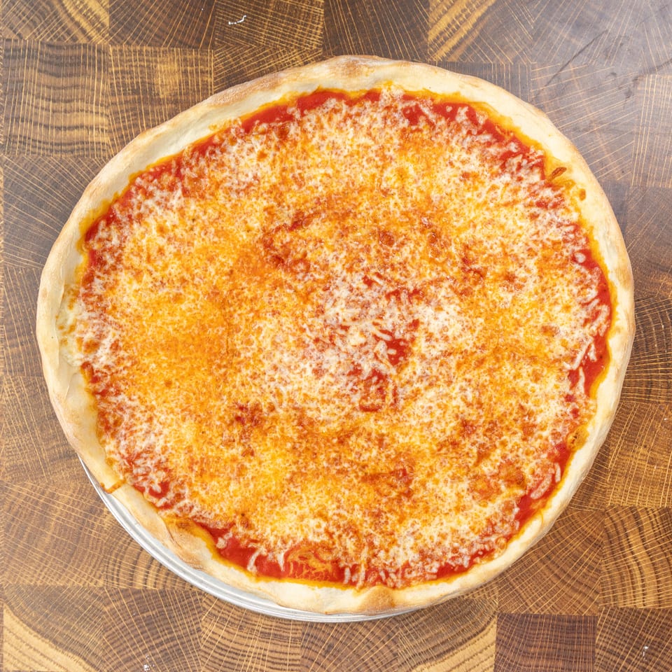 A whole cheese pizza with a golden crust and melted mozzarella, on a wooden cutting board.